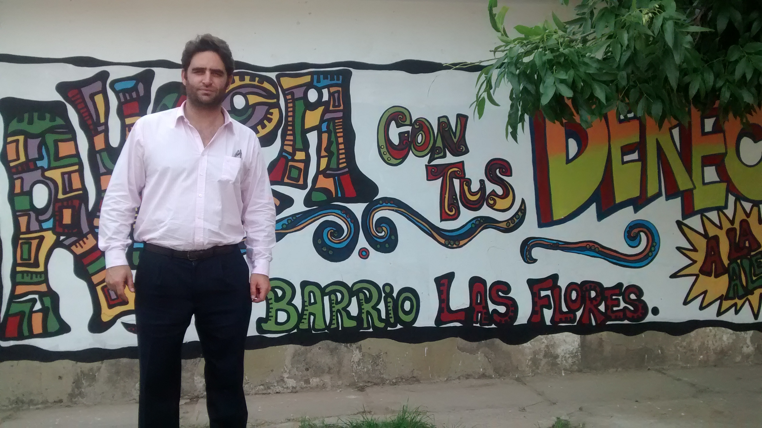 Julián Axat frente al mural pintado por alumnos y docentes de una escuela técnica del barrio rosarino Las Flores Sur.  - 